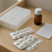 Kotak obat plastik dengan blister tablet dan botol sirup disimpan di laci kayu yang sejuk dan kering